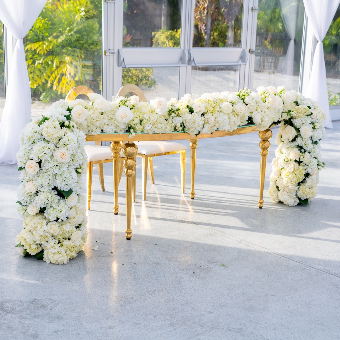 bride and groom's table at wedding reception with large while floral arrangement